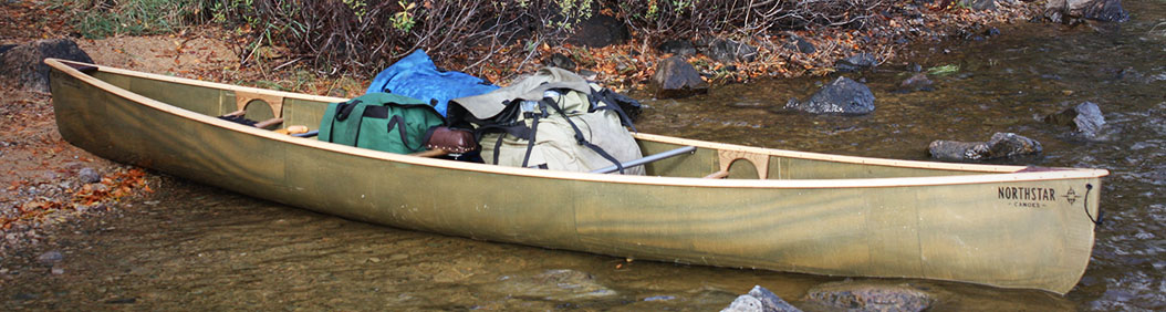 northstar canoe packed with gear at the shore of a lake