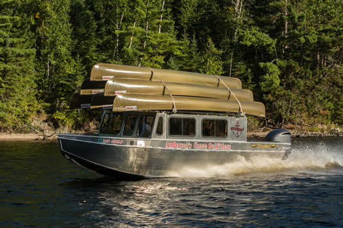 canoes on a shuttle boat, shuttle services when you're going on a boundary waters canoe trip